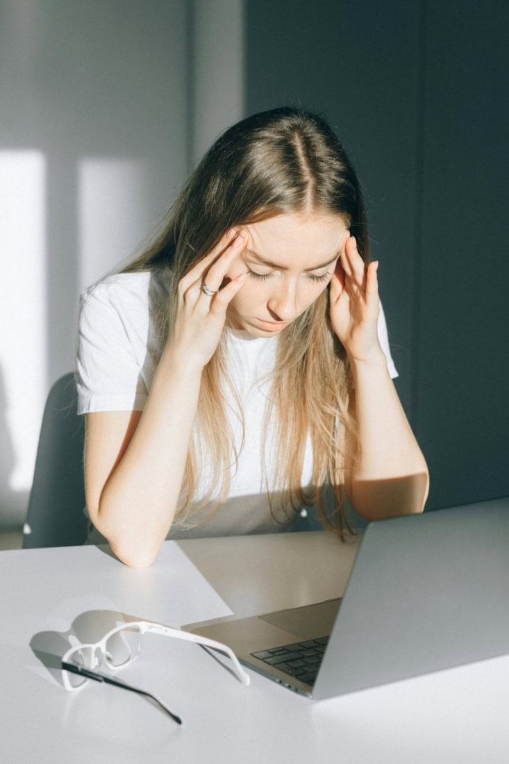 Headache complaints due to stress or fatigue, woman with painful headache at table.